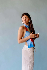 Detail of teal halter neck top with red abstract watercolor print and asymmetric hem