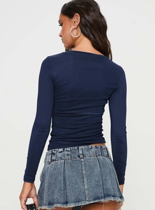 Vista posteriore del top a manica lunga blu navy e minigonna in denim a pieghe