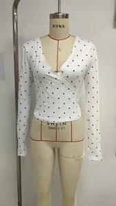 Detail of white V-neck wrap long sleeve top with black polka dots on a mannequin