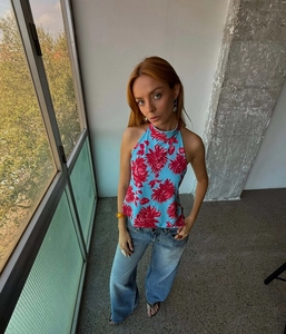 Detail of light blue halter neck top with red floral prints and irregular hem design