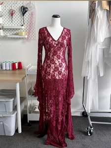 Detailed view of the sheer burgundy lace fabric and V-neck with decorative buttons