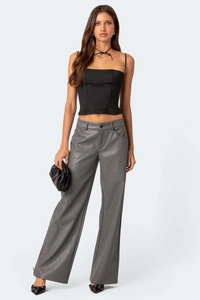 Detail eines schwarzen Corset-Tops kombiniert mit grauer Wide-Leg-Hose aus Mattleder