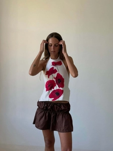 Detail of white halter top with red poppy floral print and brown ruched waist shorts