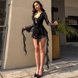 Detailed view of black lace jumpsuit with deep V-neck, ruffle trim, and long slit sleeves