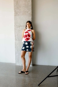 Detail of elegant white halter top with red poppy print and side-tie slit skirt