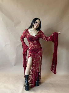 Detail of red lace dress showing rose floral patterns and side slit with flared sleeves