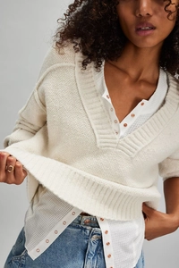 Detail of cream chunky knit cardigan with deep V-neck and metal buttons on a model
