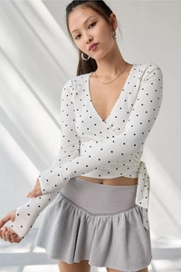 Detail of white wrap top with black polka dots, deep V-neck and side waist tie