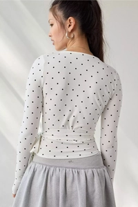 Back view of long sleeve wrap top with black polka dots and side tie detail