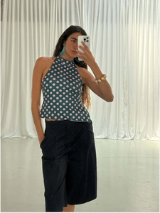 Close-up of halter sleeveless top with pink polka dots pattern on dark green fabric
