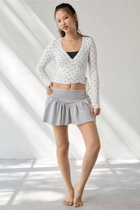 Detail of white long sleeve wrap top with black polka dots and v-neckline