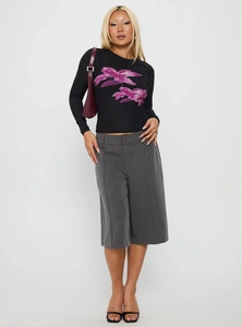 Dettaglio di una t-shirt nera a maniche lunghe con stampa floreale viola e pantaloncini
