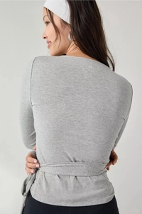 Back view of gray wrap-style long sleeve top showing knit texture and neck logo detail
