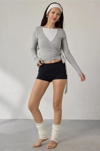 Detail of grey cross-collar long sleeve top with waist tie and black high-waisted shorts