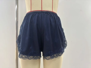 Detail of navy satin shorts featuring delicate floral lace embroidery and elastic waist