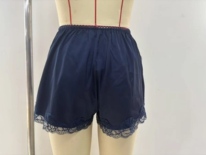 Detail view of navy blue satin shorts featuring delicate lace trim and elastic waistband