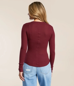Macro detail of wine red waffle knit fabric texture on slim-fit long sleeve top