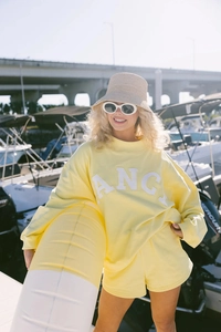 Detalle de conjunto amarillo de sudadera y pantalón con parche ANCA blanco