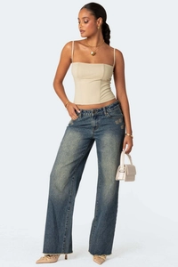 Detail van beige cropped corsettop met veststiksels en een vintage jeans met wijde pijpen