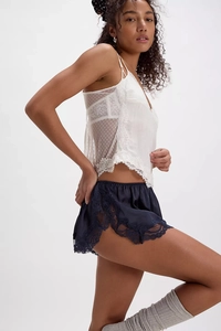 Close-up of intricate lace embroidery and silky fabric on navy blue sleepwear shorts