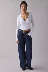 Detail of white V-neck wrap top paired with high-waisted wide-leg dark denim jeans