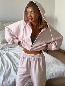 Detail of light pink zip-up hoodie and matching joggers on a model in a cozy setting