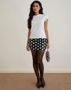 Detail of sequined polka dot mini skirt styled with white tee and silver beaded clutch bag