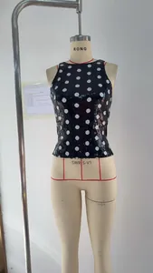 Close-up detail of black sequin sleeveless top with large white polka dot pattern