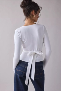 Detailed back view of white long sleeve top featuring an elegant waist tie bow design