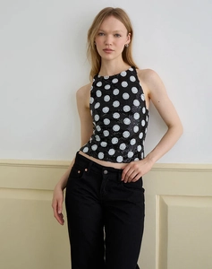 Close-up detail of a black sequined halter top with large white polka dots for women