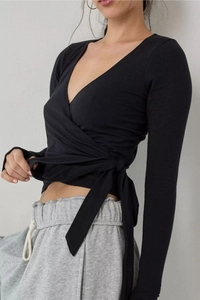 Detail of a black long-sleeve wrap top with deep V-neck and side tie-up closure