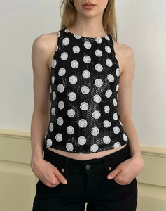 Close-up of sleeveless black sequin top with large white polka dots and glossy texture