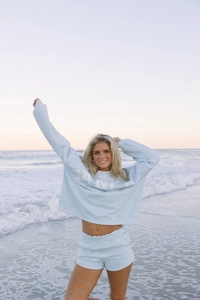 Vista detallada del conjunto de sudadera azul claro con estampado Fancy en la playa