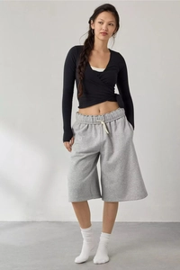 Detail of black wrap long sleeve top paired with grey drawstring wide-leg casual shorts