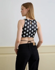 Close-up of a sequined polka dot halter top featuring a backless cross-tie design