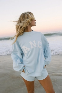 Detail of light blue sweatshirt set featuring white Angel lettering on beach background