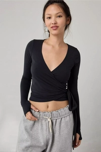 Detail of black wrap long sleeve top with thumbholes and grey drawstring jogger pants