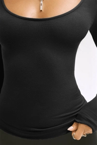 Detail shot of black ribbed long sleeve top with deep U-neckline and bodycon fit