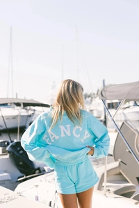 Detalle de la espalda de la sudadera azul claro con bordado FANCY blanco y pantalones cortos