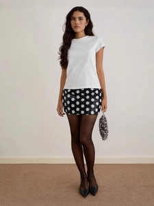 Women's chic white t-shirt and black polka dot mini skirt outfit with silver handbag