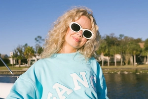 Detail of light blue sweatshirt with FANC embroidery and vintage white sunglasses
