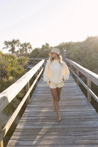 Detail view of light yellow oversized sweatshirt and drawstring shorts in a coastal setting