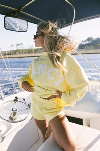 Detail of yellow sweatshirt with FANCY embroidery on a sunny yacht scene
