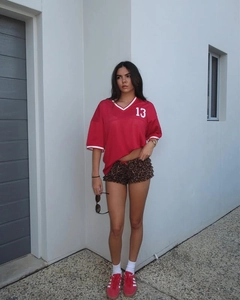 Detail of red sports jersey with white number 13 and leopard print ruffle shorts