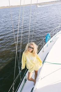 Close-up of yellow tracksuit set with ANC lettering on a white sailboat background