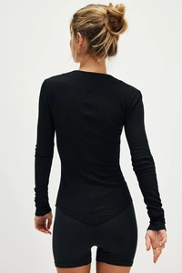 Detail view of the black slim-fit waffle knit long sleeve top with curved hem and texture