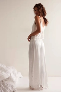 Detail of white satin sleepwear showing delicate lace trim on hem and flowing wide-leg pants