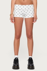 Close-up of women's slim-fit white shorts with black polka dot print and elastic fabric