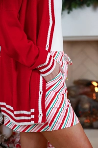 Detail of red Christmas knit cardigan with pockets and striped drawstring shorts