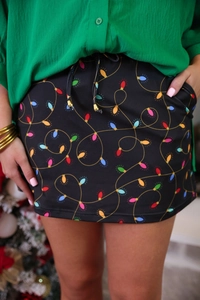 Detail of high waist Christmas mini skirt featuring colorful light bulb print and gold drawstring tips